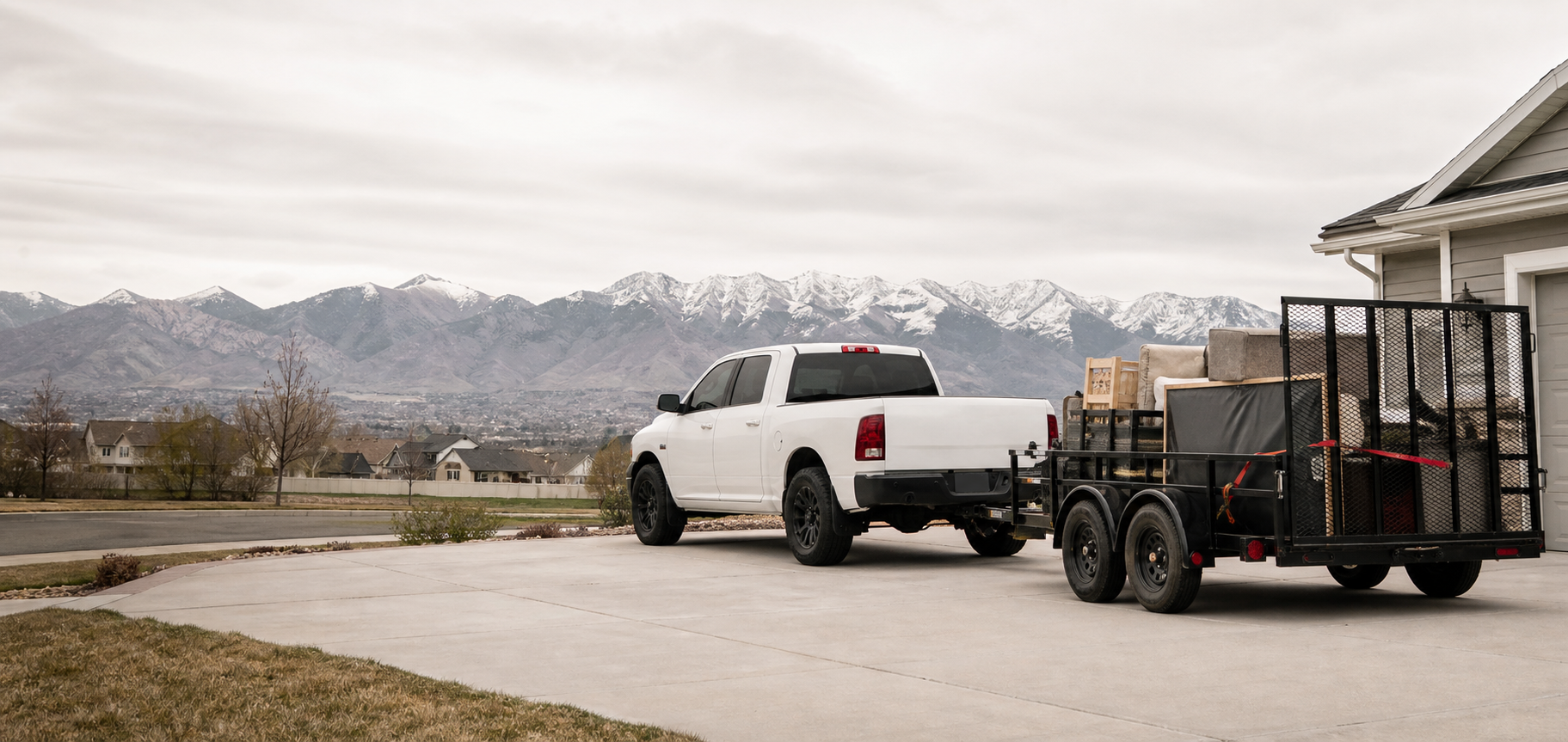 White hauling truck with trailer parked near homes along the Wasatch Front